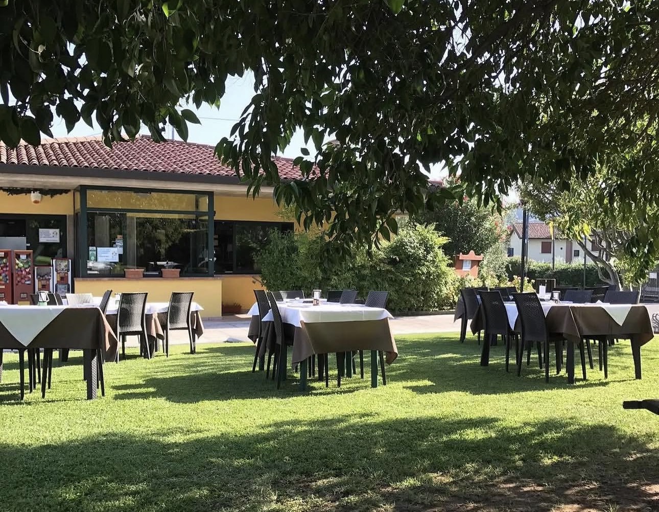 Tavoli all'aperto del ristorante CTS nel giardino ombreggiato