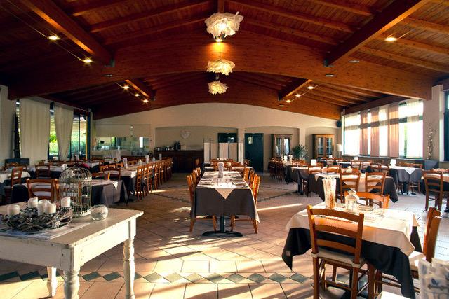 La sala interna del CTS con tavoli apparecchiati e soffitto in legno